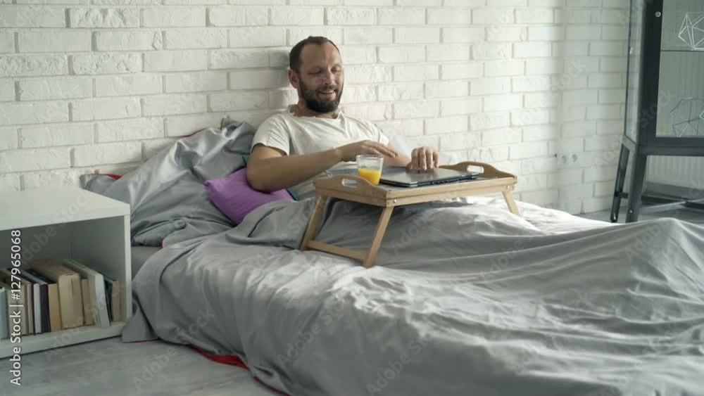 Young man finish working on laptop and drinking juice lying on bed
Young man finish working on laptop and drinking juice lying on bed