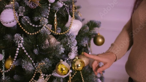 Beautiful young woman in beige sweater decorated tree.
