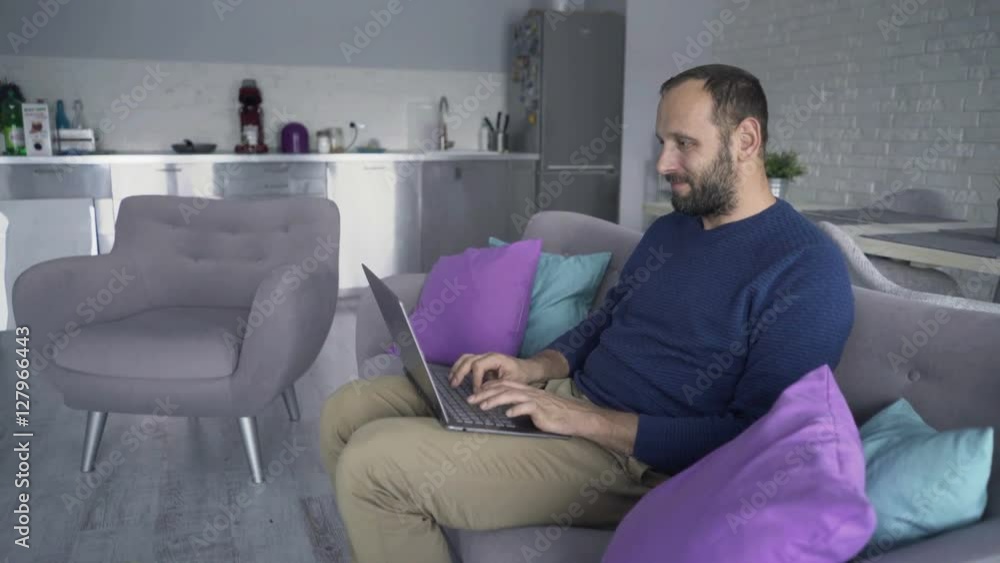Young, handsome man using laptop sitting on sofa, 4K
Young, handsome man using laptop sitting on sofa, 4K