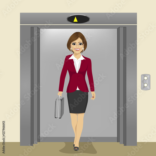 young beautiful businesswoman with briefcase coming out of office building elevator