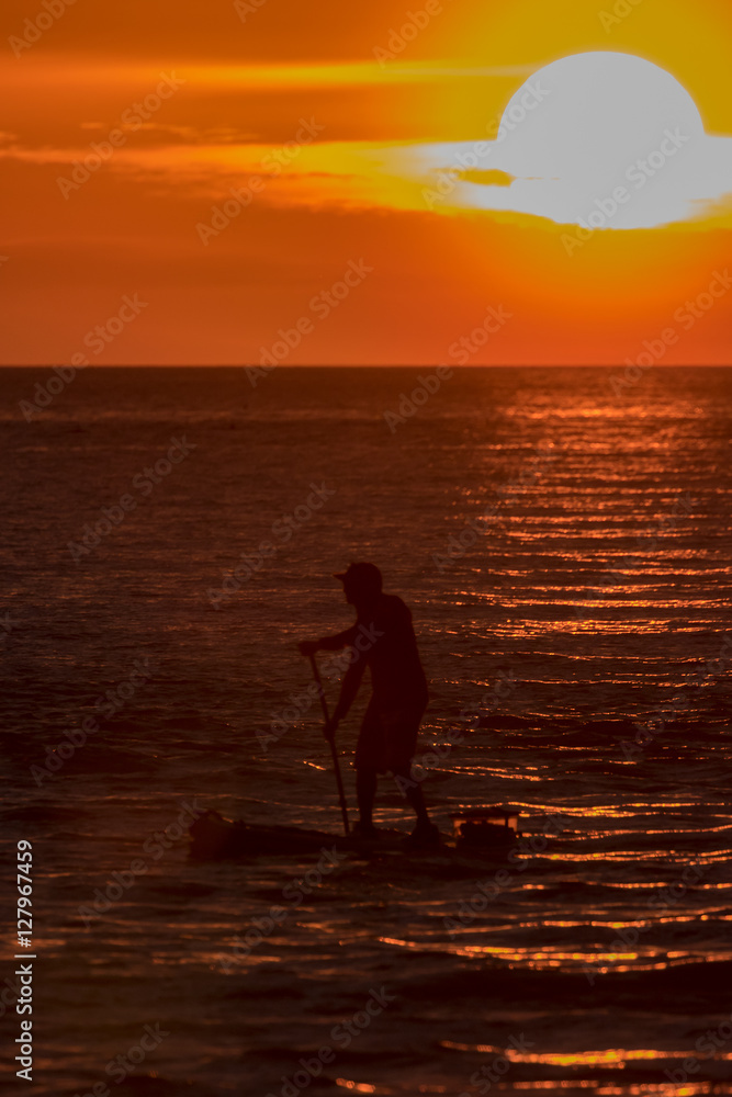 A standup paddle boarder out in the Gulf of Mexico at sunset off Blind Pass Beach, Sanibel Island, Florida.