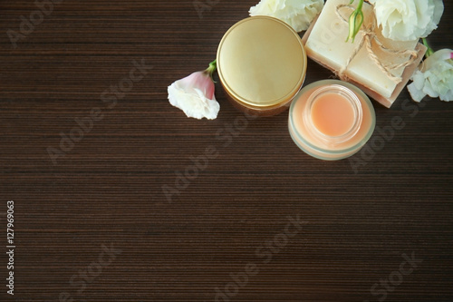 Spa composition of nutritious creams, flowers and soap on wooden background