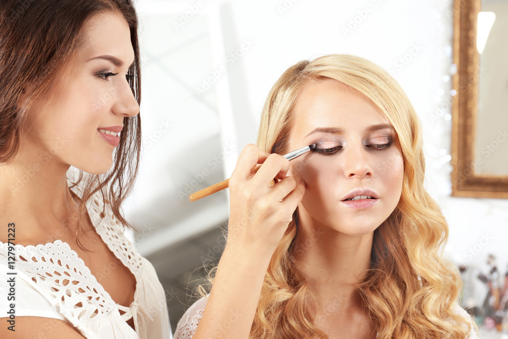 Artist applying eye shadow on beautiful woman eyes Artist applying eye shadow on beautiful woman eyes