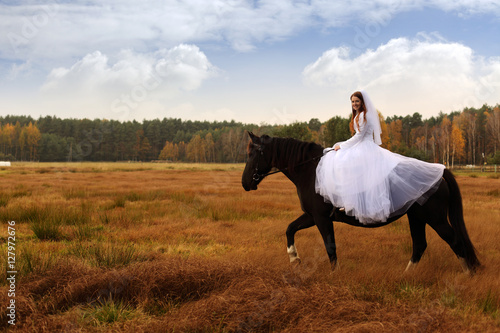 Panna młoda jeździ na koniu jesienią.