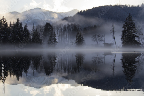 Lake Erlaufsee in Austria in Winter with fog, clouds and sun with nice reflection
