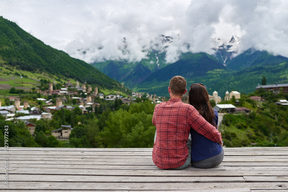 Young couple in love sitting on roof and admire scenery