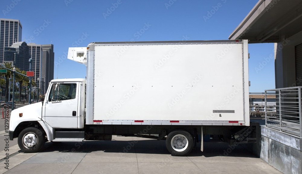 Parked refrigerated truck at loading dock under blue sky. Horizontal. Parked refrigerated truck at loading dock under blue sky. Horizontal.