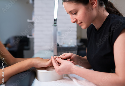 woman manicurist trims cuticles on the nails of client.