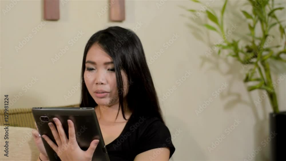 Young woman reading on a tablet computer in her home. Young woman reading on a tablet computer in her home.