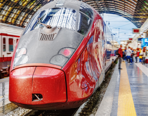 Trenitalia Frecciarossa (red arrow) on platform of Milan Central Station. This high speed train can reach 300 km/h and operate Turin-Milan-Bologna-Florence-Rome-Naples route. Passanger staying nearby. photo