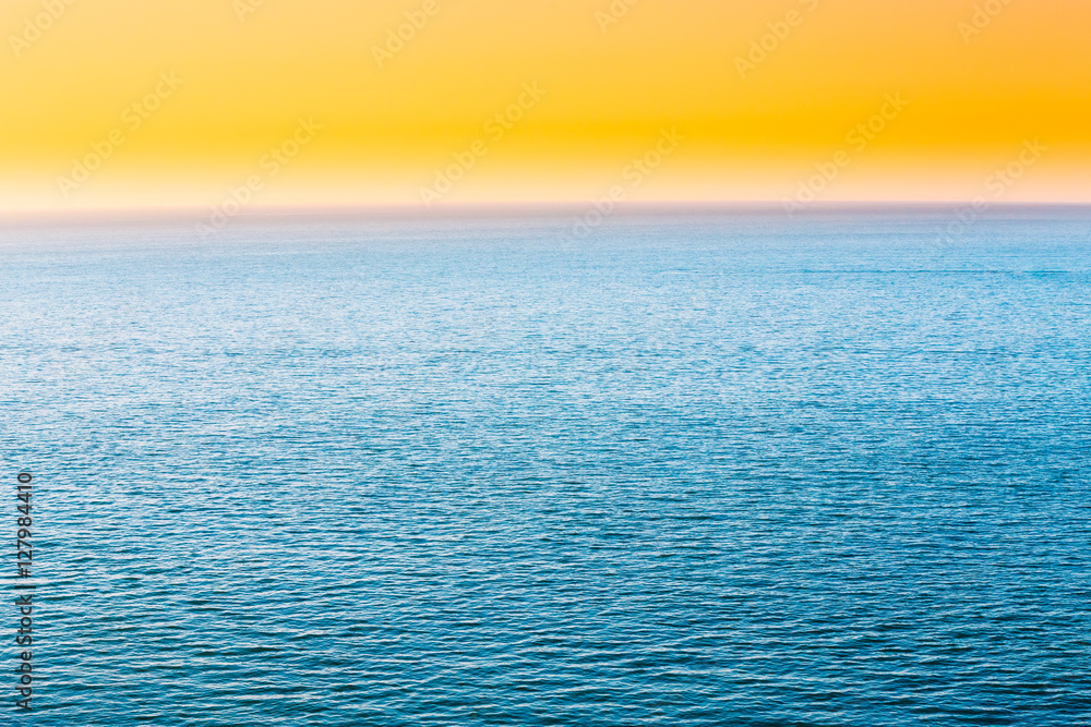 Obraz premium Blue Sea Or Ocean And Yellow Clear Sunset Or Sunrise Sky Background