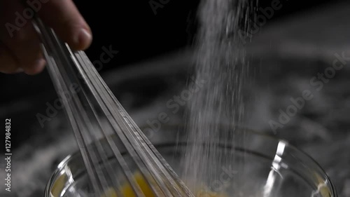 chef mixes the eggs with the sugar black background. photo