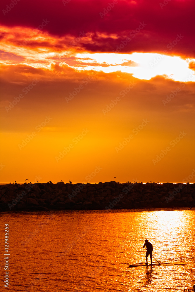 Lone paddle boarder at sunset