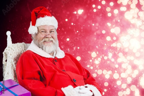 Composite image of santa claus sitting on chair with sack