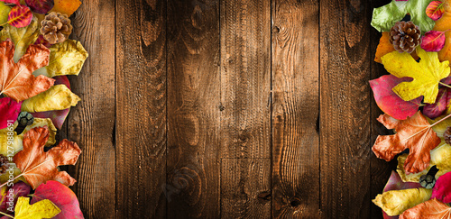 Autumn Leaves over a Natural Dark Wooden background. Old dirty wood tables or parquet with knots and holes and aged partculars.