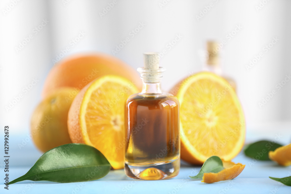Bottle with essential oil, oranges and leaves on blue table Bottle with essential oil, oranges and leaves on blue table