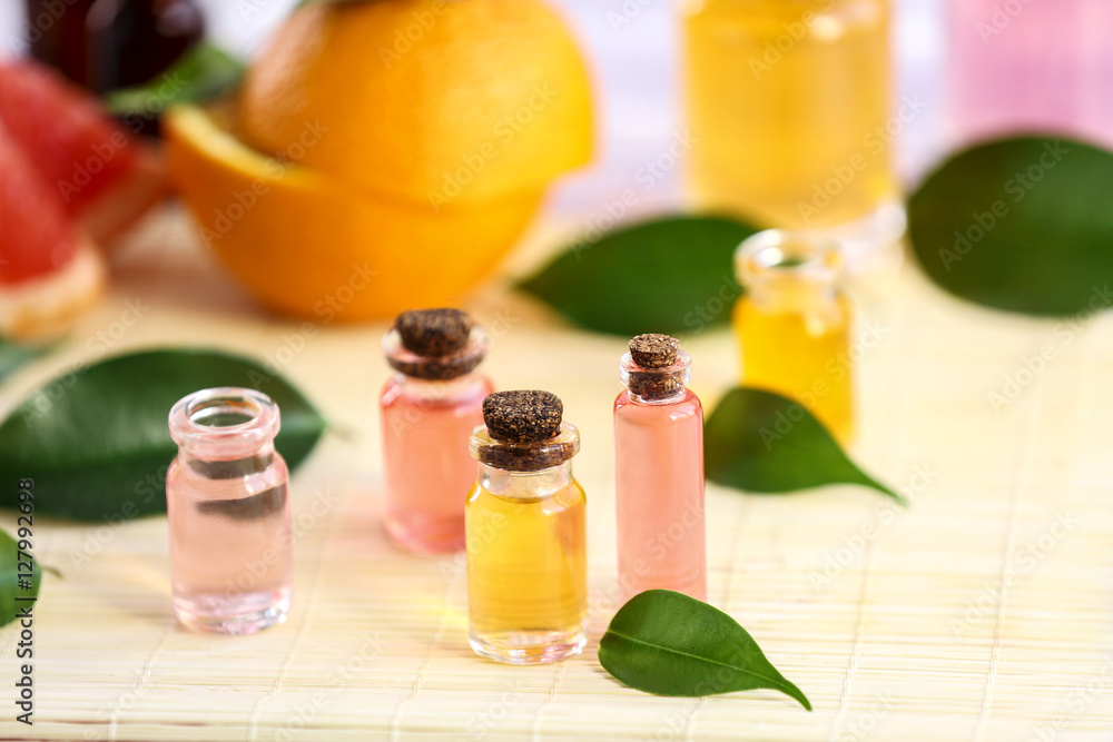 Bottles with essential oil, fruits and leaves on bamboo napkin Bottles with essential oil, fruits and leaves on bamboo napkin