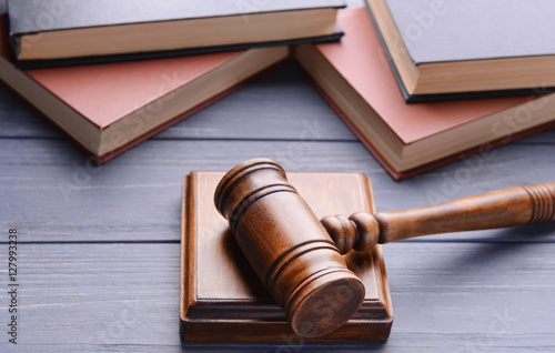 Gavel with sound block and books on wooden background, closeup