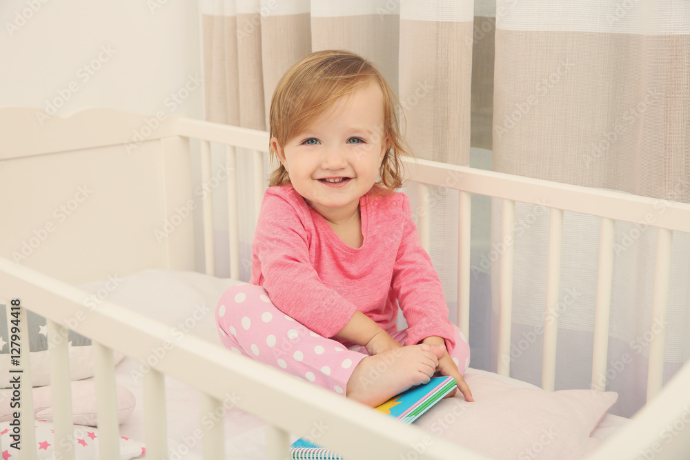 Cute little girl with book in cradle at baby room Cute little girl with book in cradle at baby room