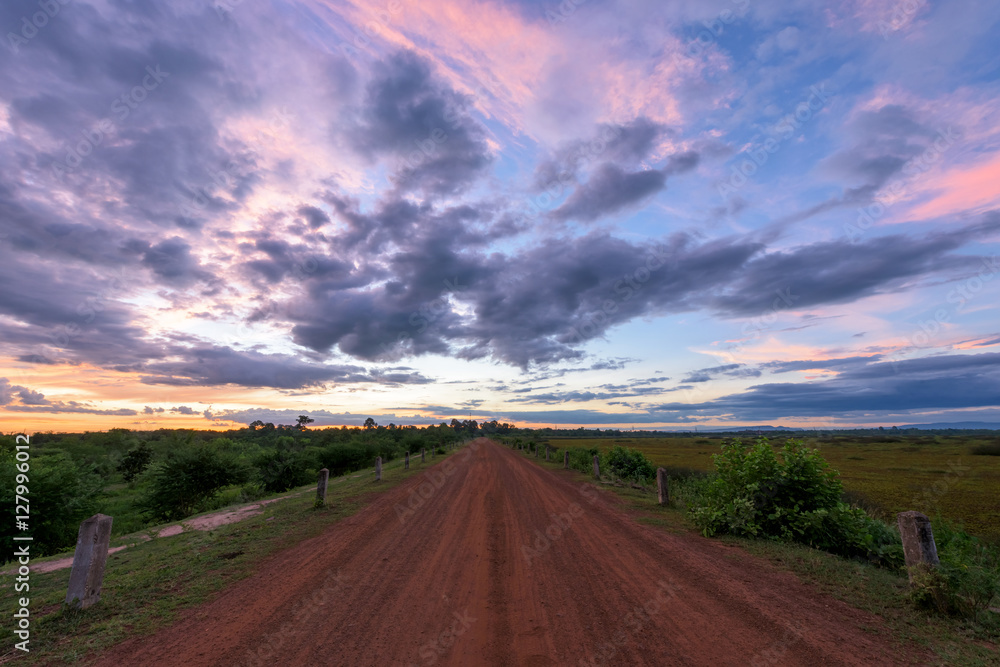 Rural dusty countryside road with sunset