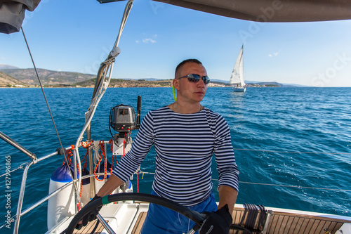Skipper at the helm controls of a sailing yacht.
