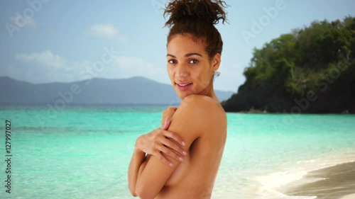 Lovely African woman standing topless on caribbean beach of bahamas. photo