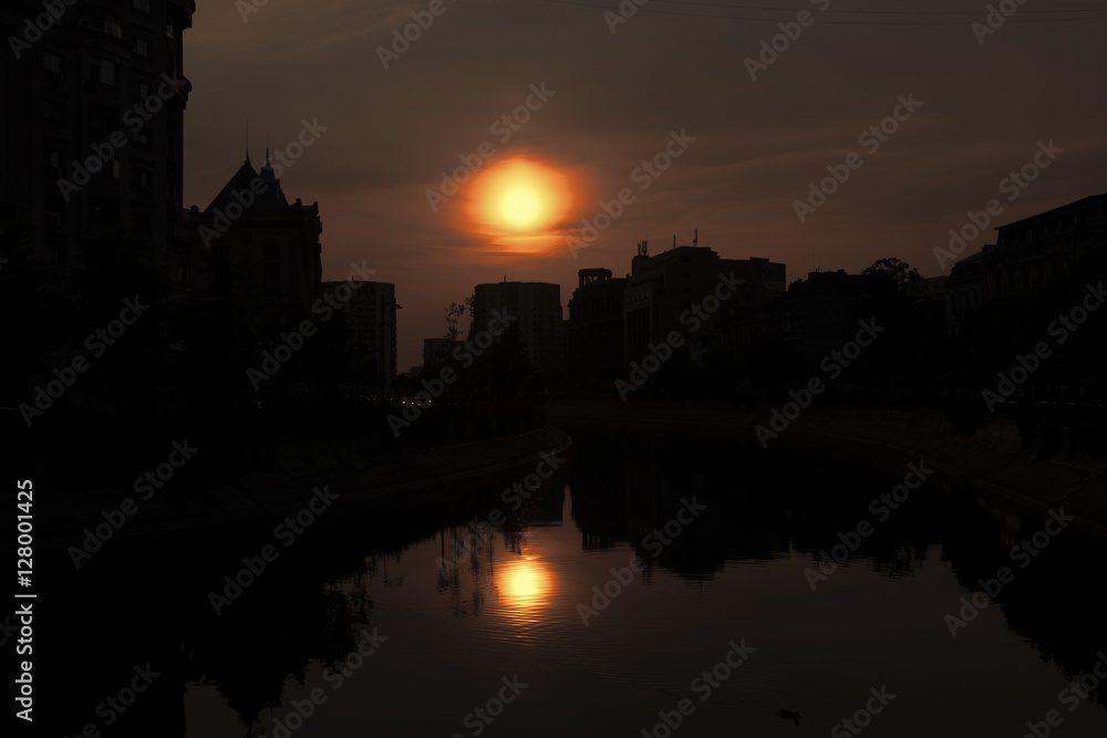 Abstract city skyline. Sunset time view of city of Bucharest, reflected in Dambovita River.