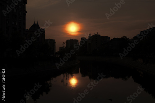 Abstract city skyline. Sunset time view of city of Bucharest, reflected in Dambovita River.