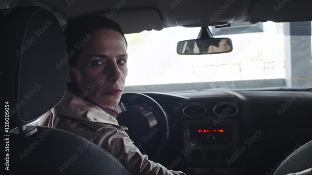 Shot from backseat of vehicle of mature woman reversing car into parking spot, then leaving Shot from backseat of vehicle of mature woman reversing car into parking spot, then leaving