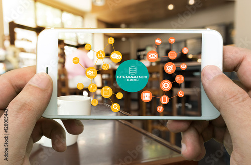 Data Management Platform (DMP) , Marketing and crm concept. Hand holding mobile phone , infographic , texts and icons on coffee retail shop background.  photo