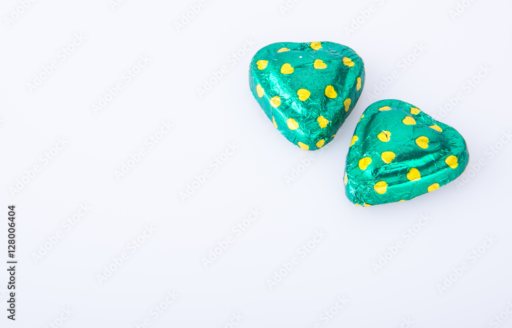 Chocolate or green foil heart-shaped chocolate on a background. Chocolate or green foil heart-shaped chocolate on a background.