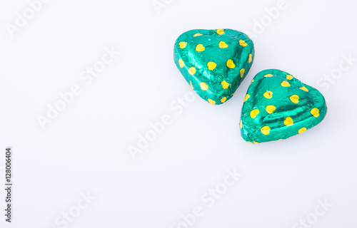 Chocolate or green foil heart-shaped chocolate on a background.