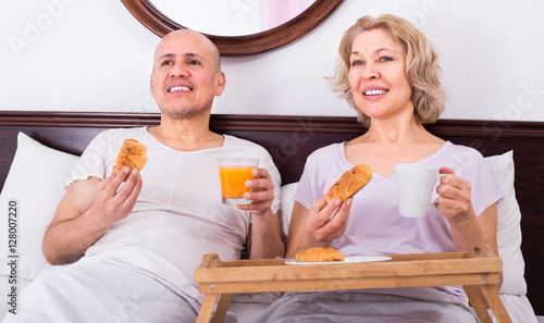 Mature couple having breakfast in bed. photo