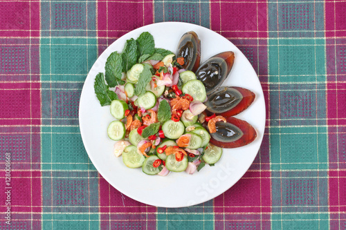 Spicy cucumber salad with dried shrimp and  preserved egg. photo