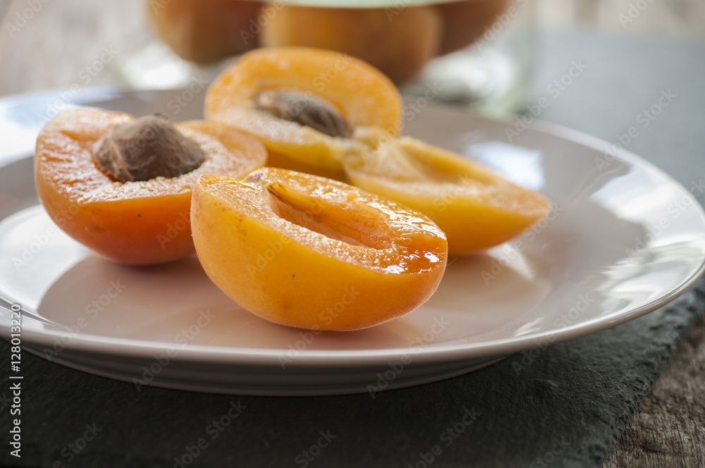 Whole orange apricots with red blush, from above, space for text. Open apricot with stone and leaves. On rustic white wood. Whole orange apricots with red blush, from above, space for text. Open apricot with stone and leaves. On rustic white wood.