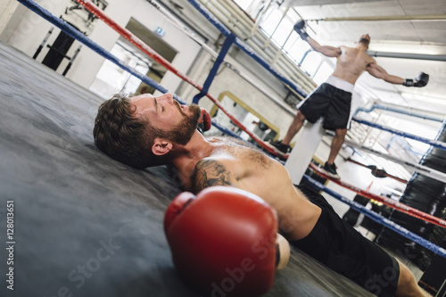 Knocked out boxer lying in boxing ring photo