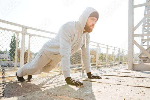 Handsome young fitness man doing push-up exercises outdoors