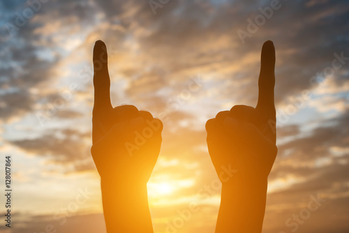 Silhouette of hand shape with sky sunset background.