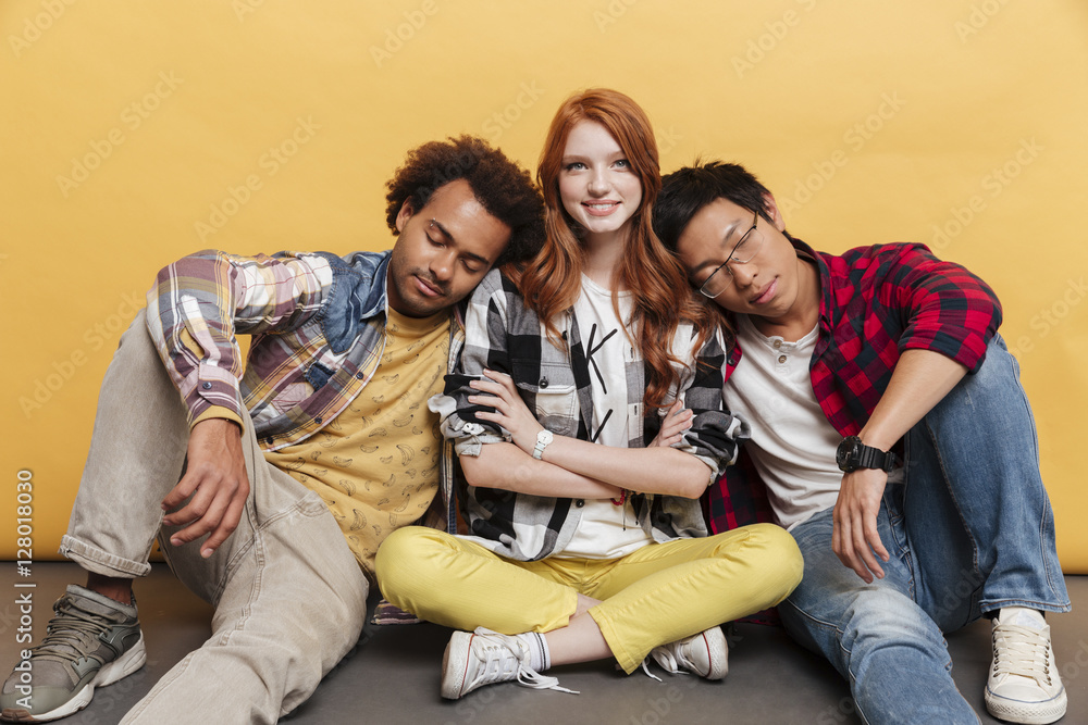 Fototapeta premium Two tired young men sleeping on shoulders of smiling girl
