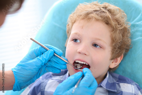 Male dentist examining a little boys teeth at the dental clinic.