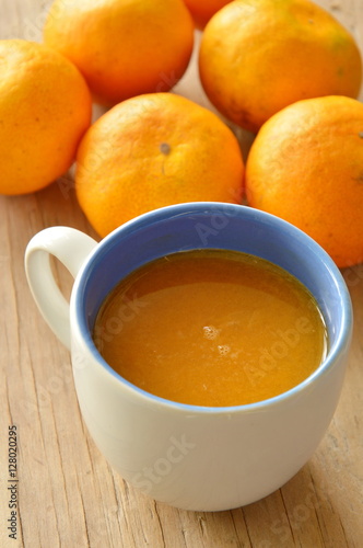 orange juice in cup and tangerine on wooden table