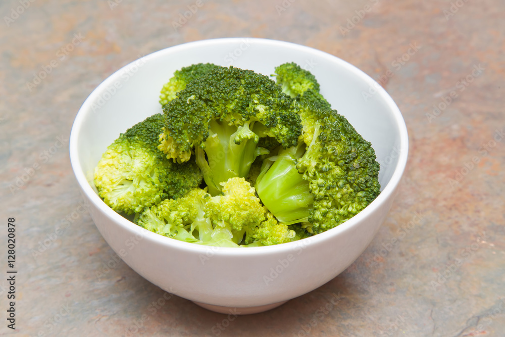 Fresh, green and healthy broccoli in the white bowl ready for cooking in the kitchen. Healthy eating lifestyle. Focus point in the middle. Fresh, green and healthy broccoli in the white bowl ready for cooking in the kitchen. Healthy eating lifestyle. Focus point in the middle.