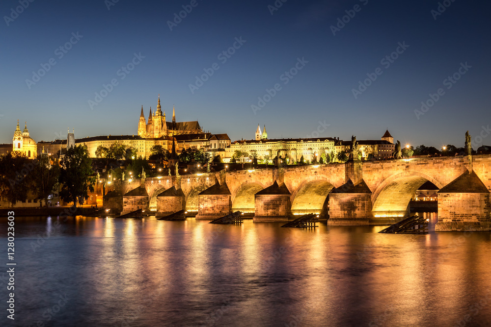 Pretty night time illuminations of Prague Castle, Charles Bridge and St Vitus Cathedral reflected in the Vltava river running through the heart of the city of Prague in the Czech Republic.