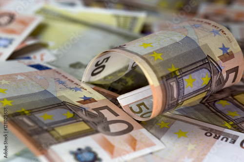 Half rolled fifty euro banknote on fifty euros banknotes background. Close up shot, Selective focus.