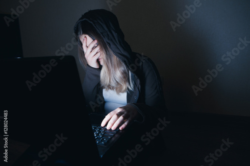 Obraz na plátně sad and scared female teenager with tablet computer and laptop suffering cyberbu