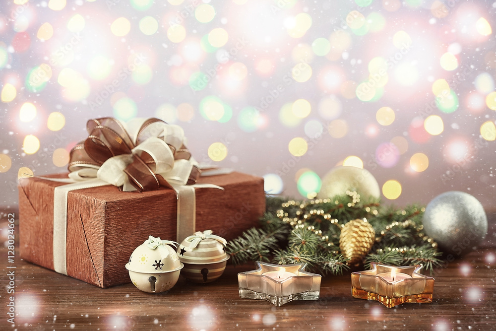 Christmas gift and festive decor on wooden table against blurred lights background. Snowy effect Christmas gift and festive decor on wooden table against blurred lights background. Snowy effect