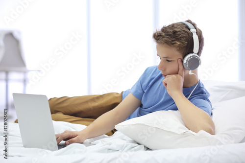 Boy laying with computer on bed