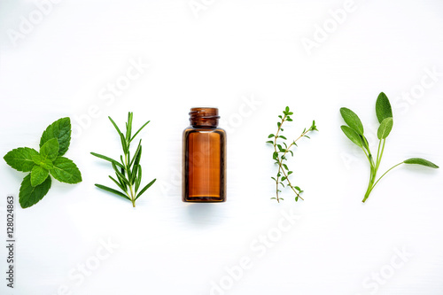 Bottle of essential oil with fresh herbal sage, rosemary, lemon