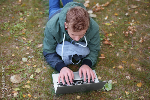 Teenager with laptop lying ...