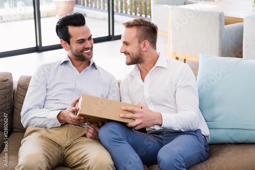 Smiling man offering gift to his boyfriend 